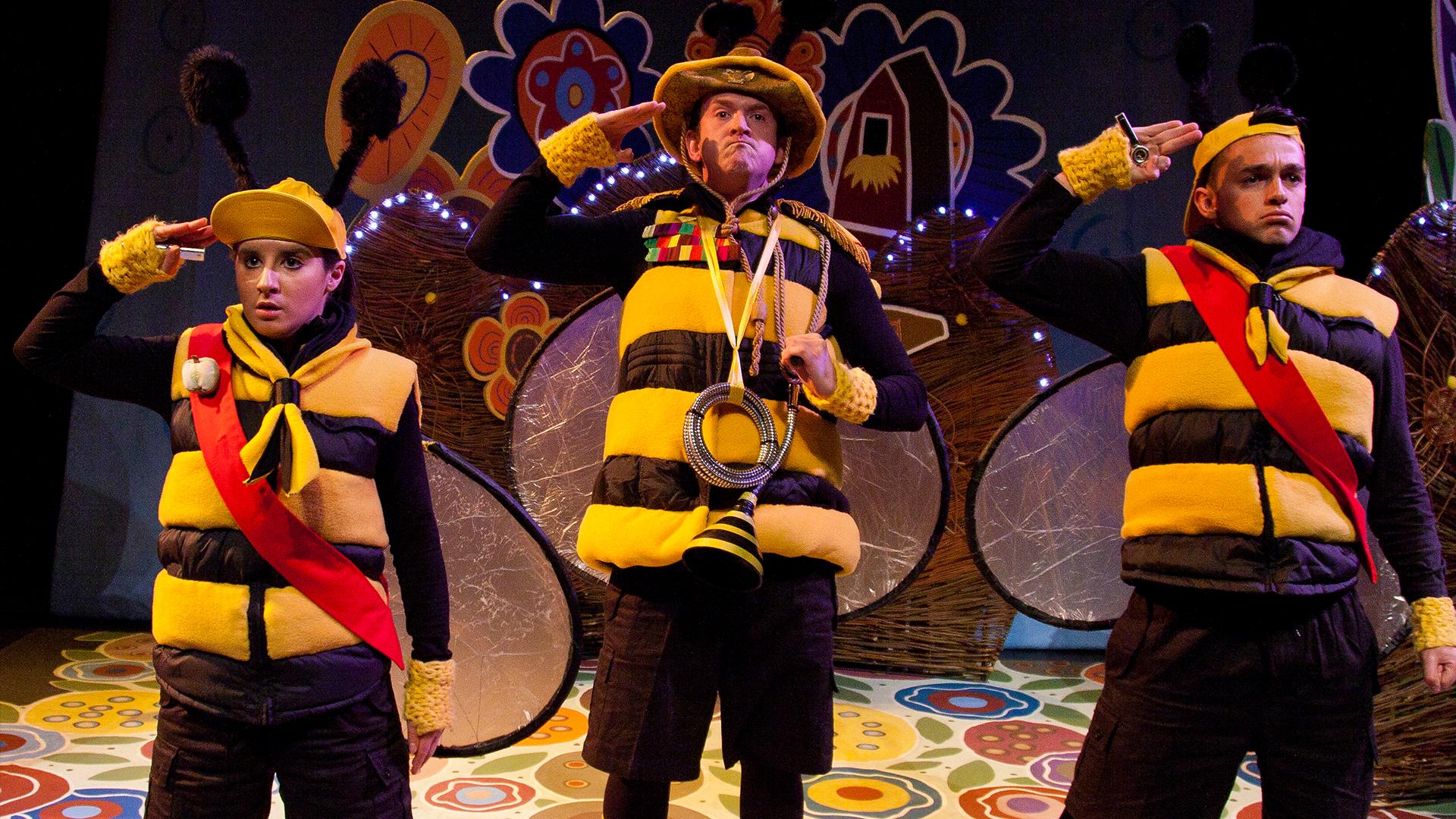 Three people dressed as bees standing saluting