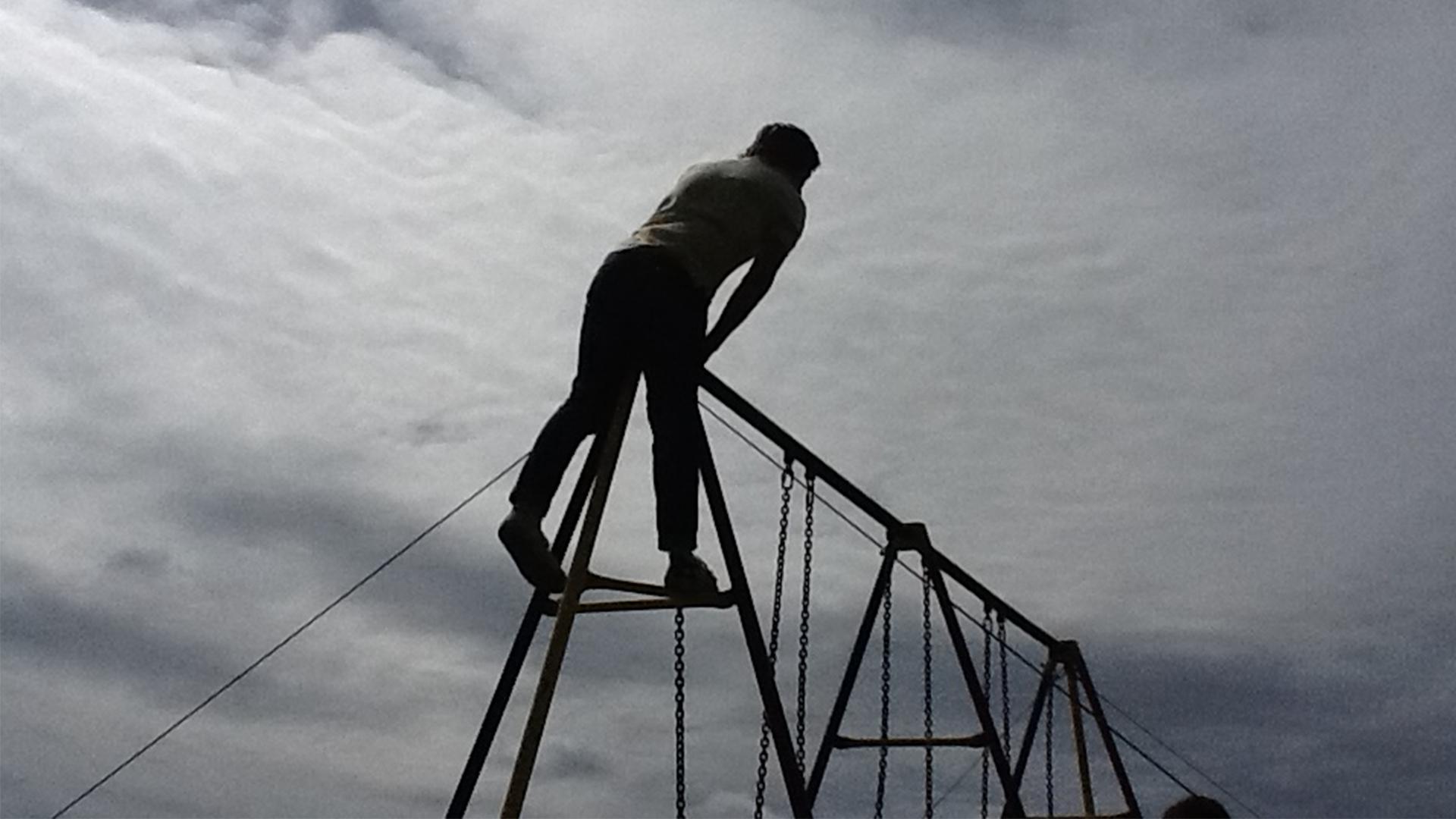 A boy standing up high on a climbing frame