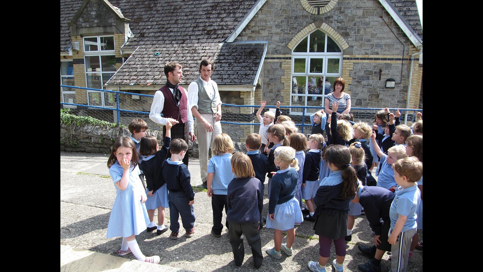 Group of primary school children with the actors in costume outside the school