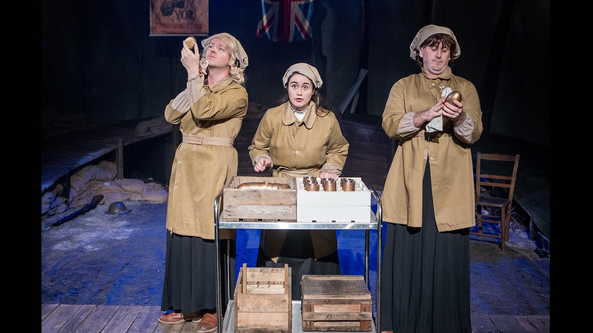 Three actors, one woman, two men, dressed as female munition factory workers