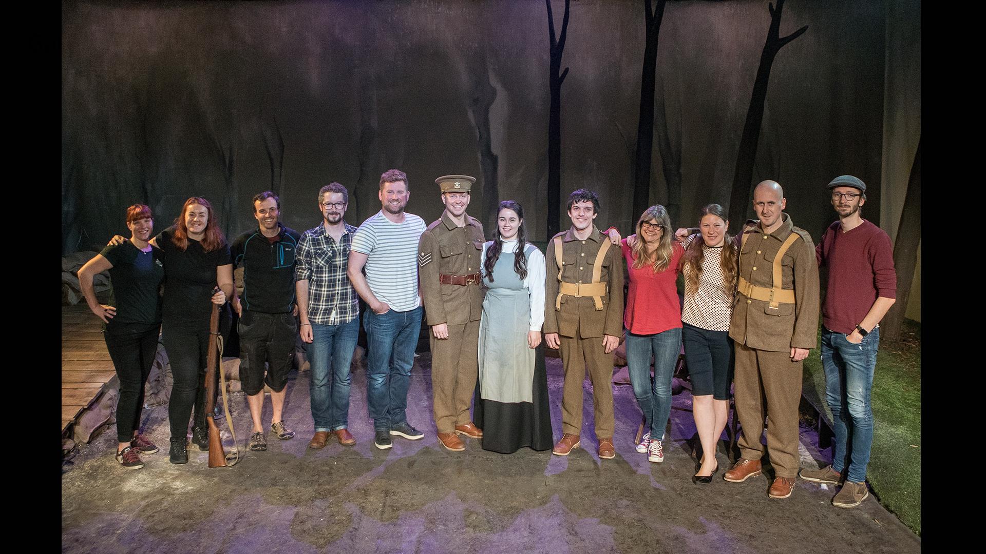 The cast and production team standing in a line smiling at the camera