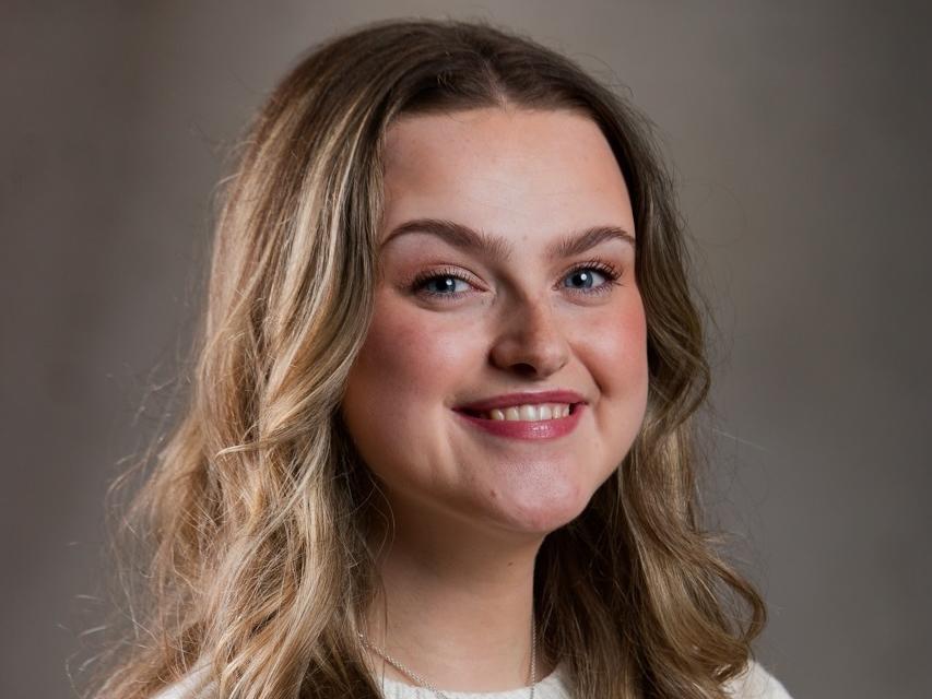 Siân's headshot - a white woman in her mid twenties with light brown, long curly hair