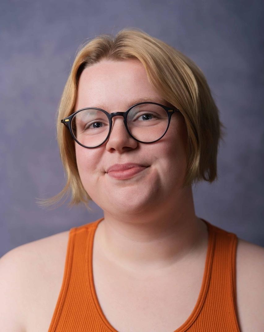 White person with short blonde hair just past their ears and round glasses