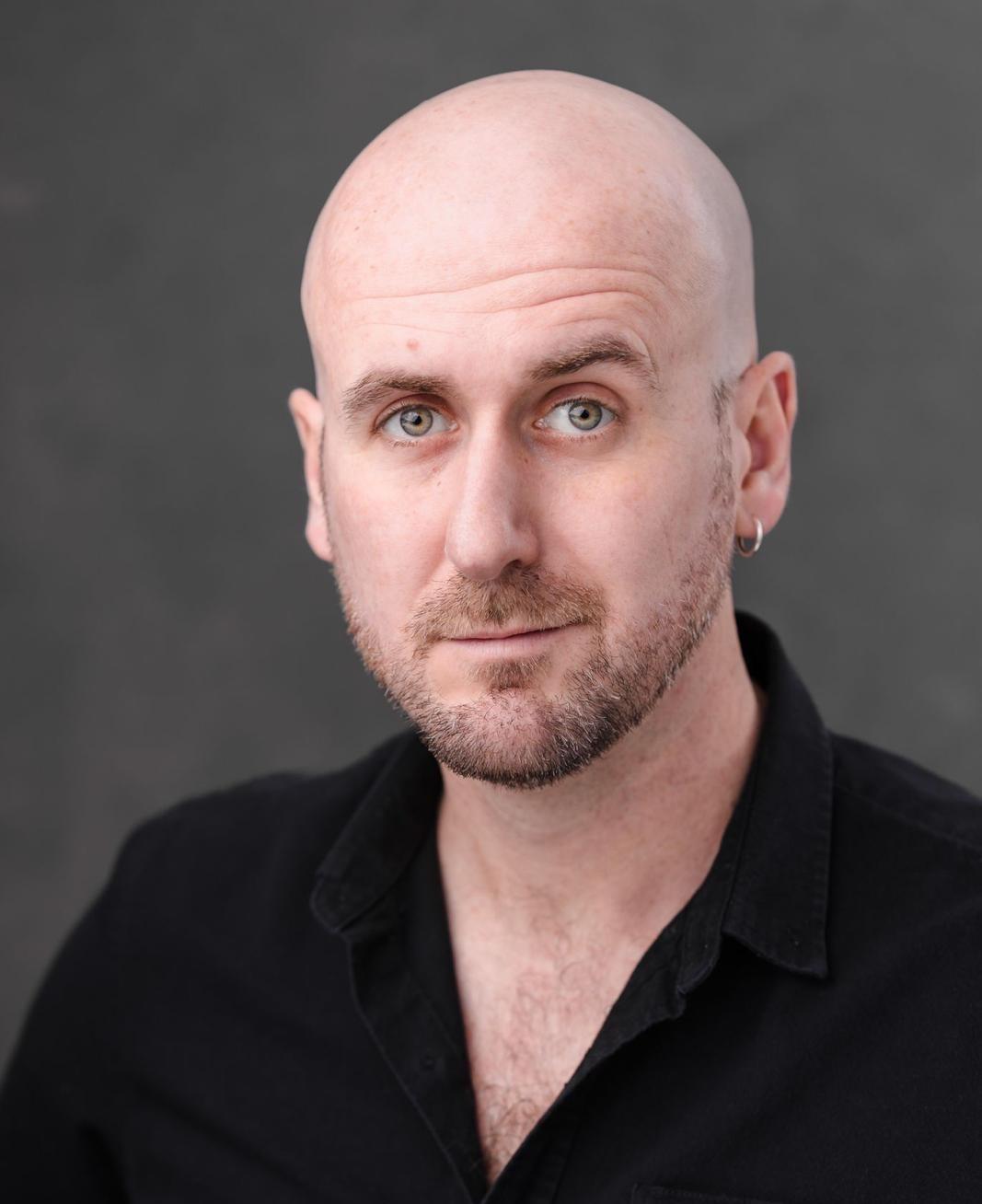 White man in his thirties, bald with some stubble