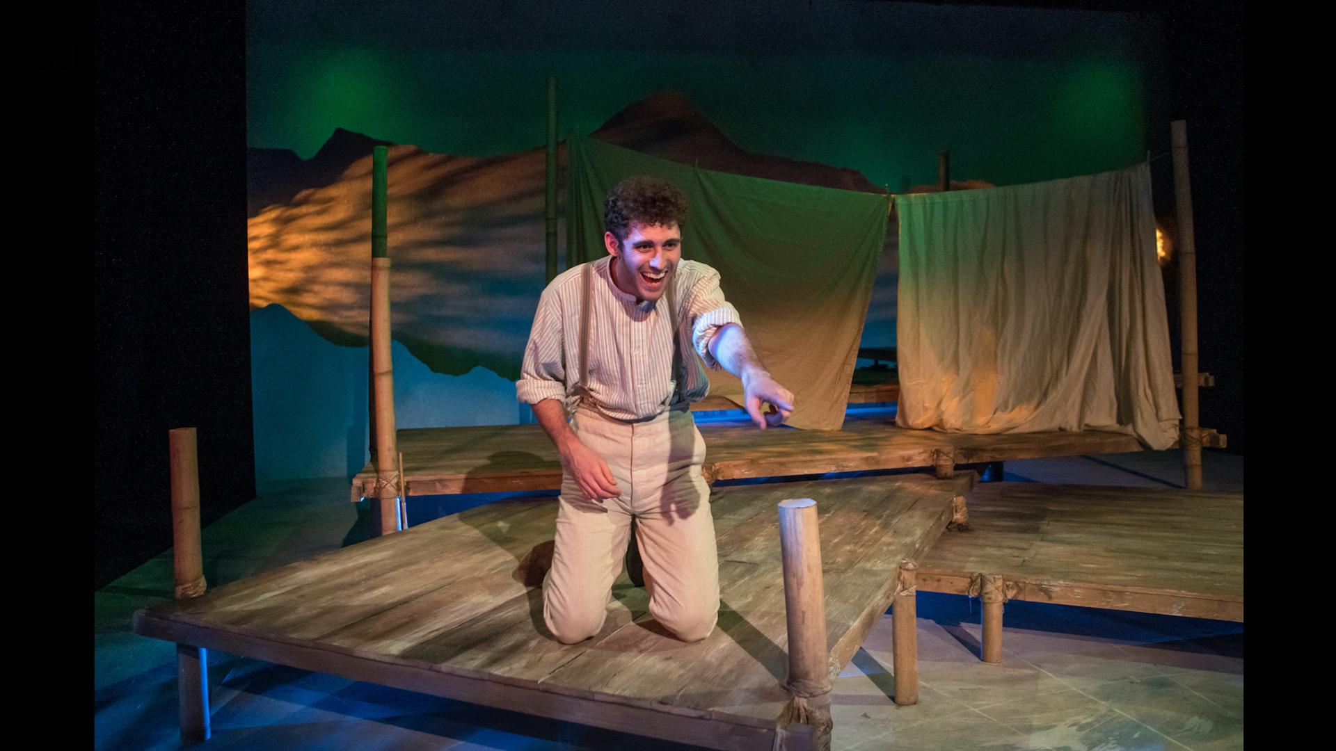 Actor playing Wallace kneeling on the wooden deck.