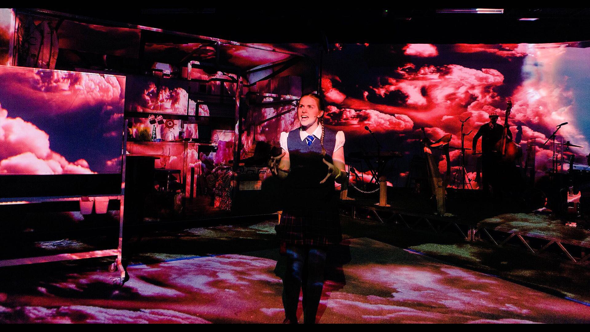 A schools girl standing in the centre of a projected storm