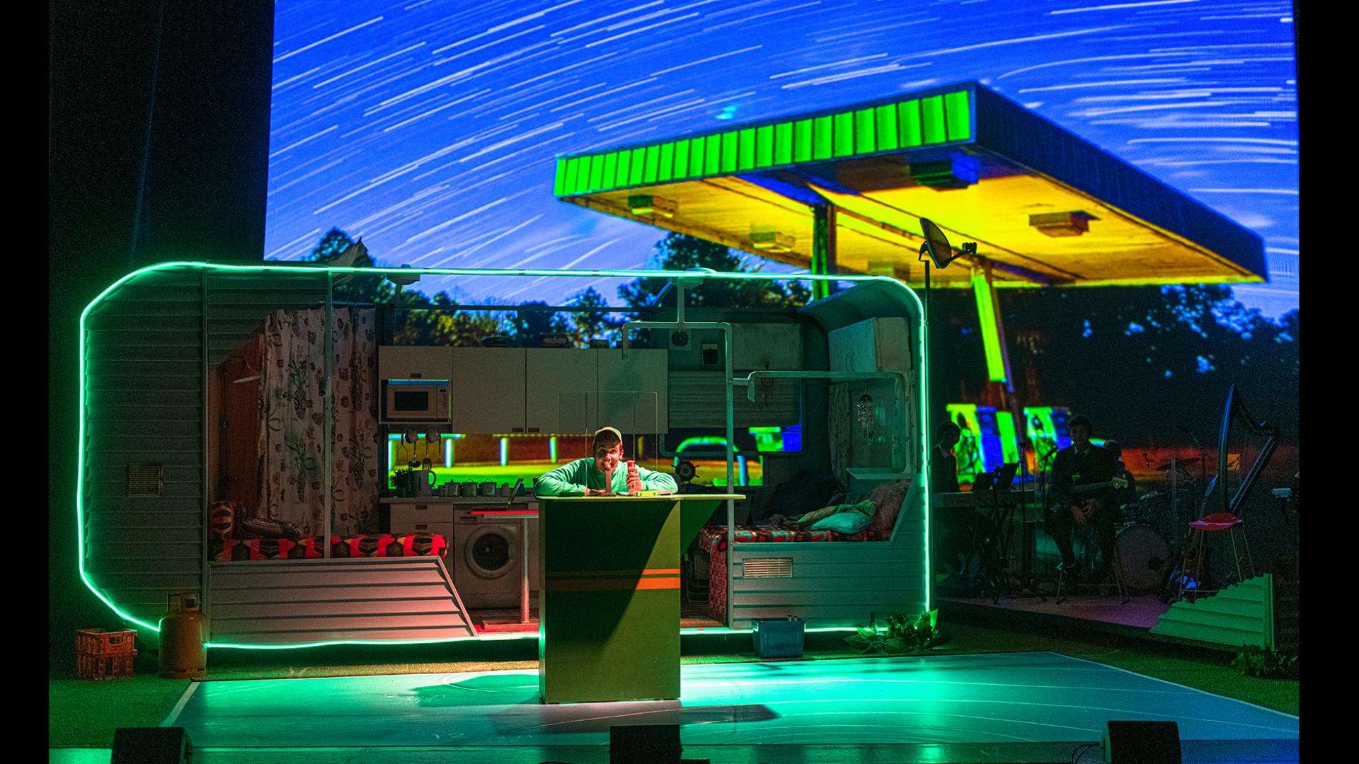 A projection of a petrol station with a counter and young boy behind it