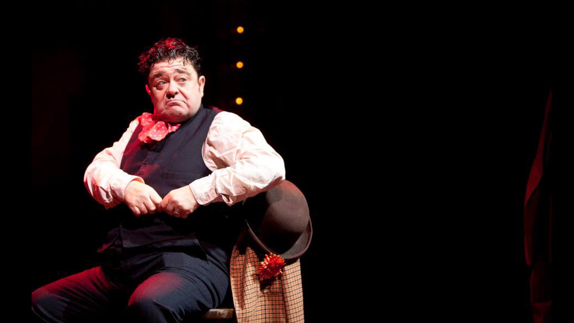 A man sat in a chair with a bowler hat