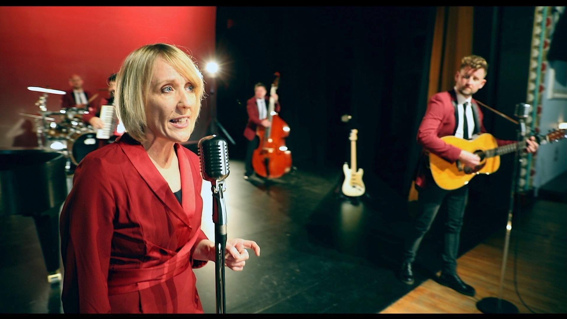 Two singers dressed in red, one playing a guitar