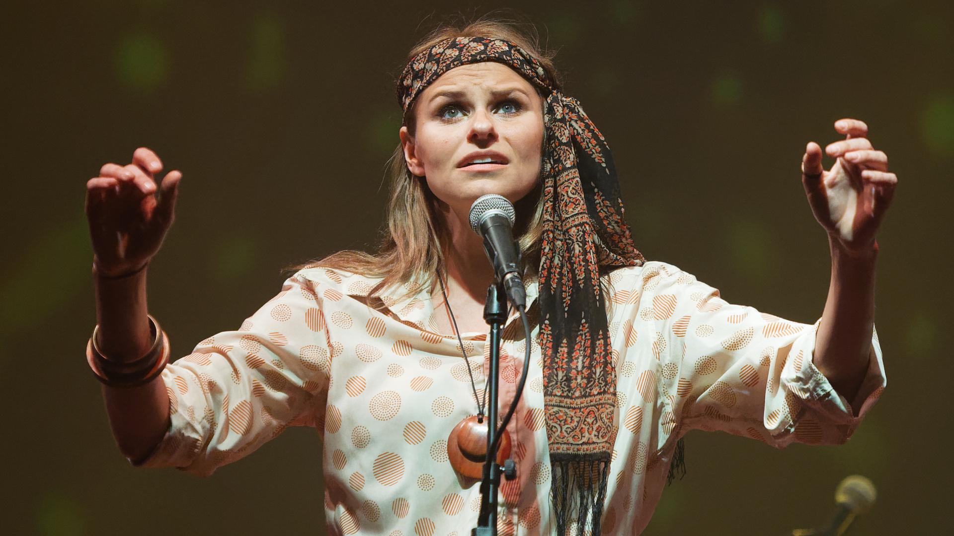 Actor Georgina White singing with her arms in the air