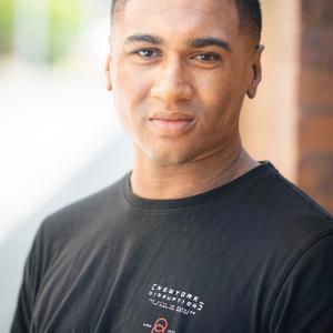 Black man with short black hair wearing a black t shirt