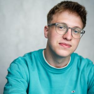 White man in his early twenties with short, dark blonde hair and glasses