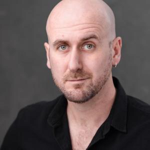 White man in his thirties, bald with some stubble
