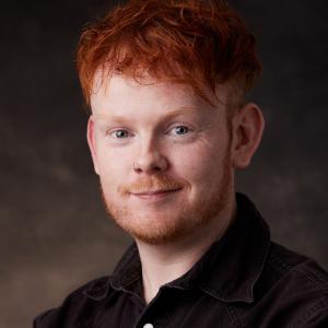 White man in his thirties with short red hair and facial hair