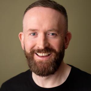 White man with brown hair and facial hair