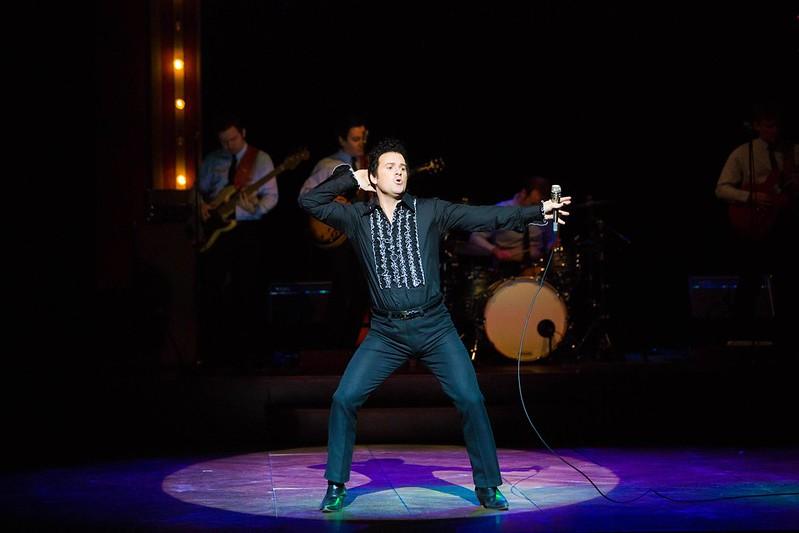 Image of actor dressed as Tom Jones dancing in front of a band