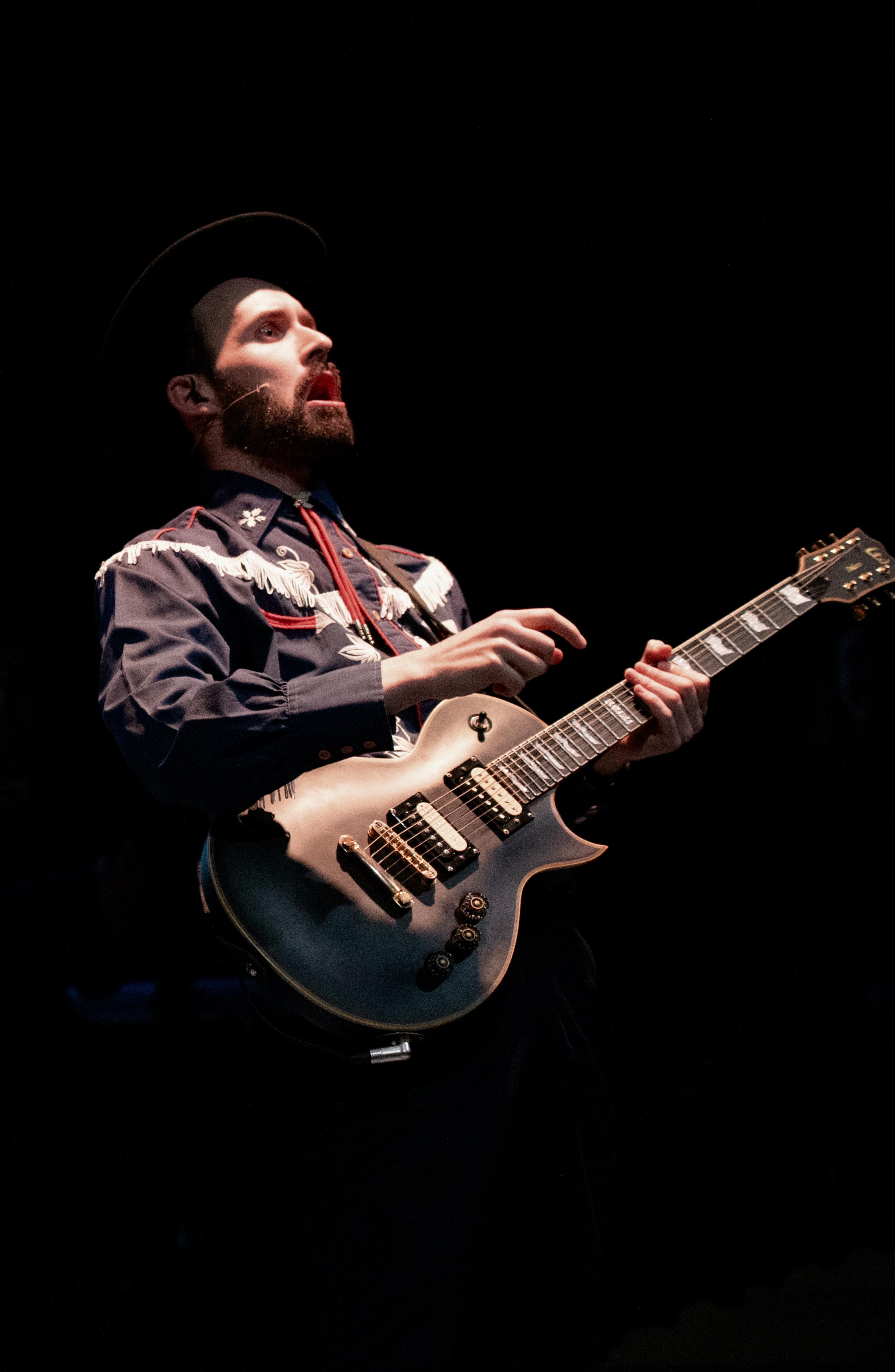 Man dressed as a modern day American cowboy holding a guitar